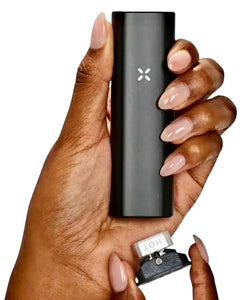 A PAX Plus Vaporizer in a person's hand with the chamber open.